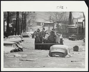 Revere Scoop Loader becomes rescue craft as it evacuates flooded residents, including a mother and child, center, from Jones road, Beachmont.