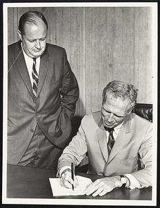 Mayor White signing paper on Boston Stadium and Bra. Pres. Hale Champion is looking on