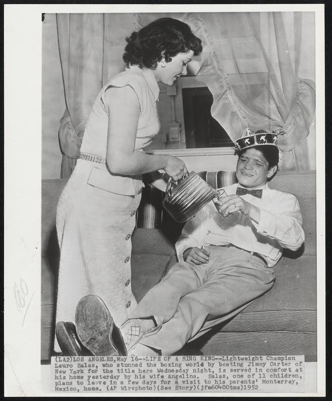Life of a Ring King -- Lightweight Champion Lauro Salas, who stuned the boxing world by beating Jimmy Carter of New York for the title here Wednesday night, is served in comfort at his home yesterday by him wife Angelina. Salas, one of 11 children, plans to leave in a few days for a visit to his parents' Monterrey, Mexico, home.