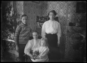 Young man, young woman, grown woman, and child. Interior: toys on desk?