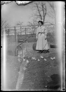 Woman with chickens. Fence in background
