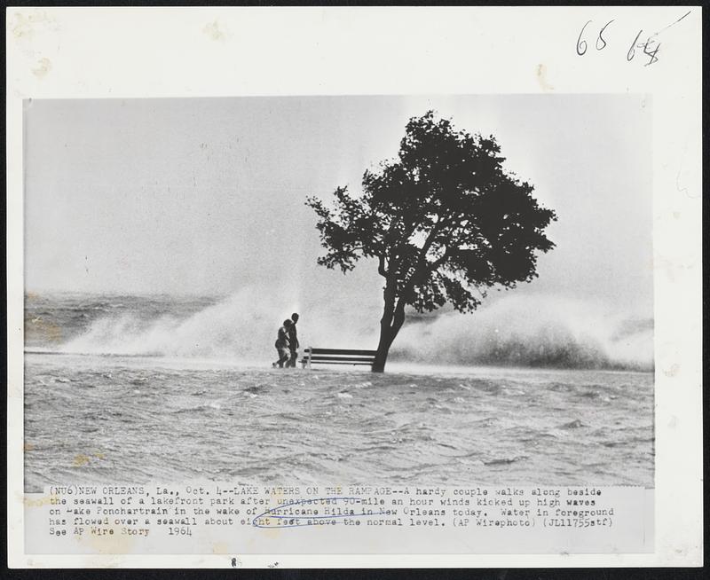 Lake Waters on the Rampage Age-- A hardy couple walks along beside the seawall of a lakefront park after unexpected 90-mile an hour winds kicked up high waves on Lake Ponchartrain in the wake of Hurricane Hilda in New Orleans today. Water in foreground has flowed over a seawall about eight feet above the normal level.