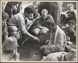 Japanese prisoners, (right), taken during the fighting at Iboki on New Britain, munch field rations and while away the time playing a tic-tac-toe game with their marine captors