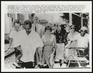 Hong Kong: With his son Louis, 3, in his arms, U.S. Korean War turncoat Clarence C. Adams crosses into Hong Kong 5/26 after more than 12 years in Communist China. He said he was going to Tennessee to see his mother. At his left is his Chinese wife and their daughter, Della, 7. In the background (white suit) is an unidentified U.S. Consulate official.
