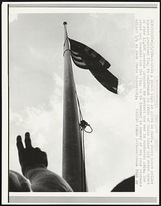 A peace sign is given as Mass. State House police lowered American flag to half-mast in front of State House 5/5 where crowd of some 15,000 persons gathered to protest the war in southeast Asia. The crowd had chanted for the flag to be lowered in memory of the four students killed 5/4 at Kent State University.