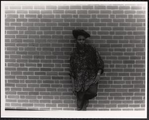 Young man in printed shirt posing against brick wall