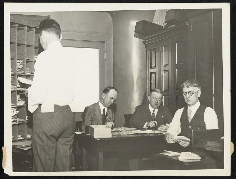 Clerks in Boston Post Office sorting mail that is to go out tomorrow (Sunday) on the First Flight of the new air mail service from Boston to Albany. The mail for this flight all bears the official "cachet" ordered by the Post Office Department at Washington, and is mostly stamp collectors' mail, which they themselves have sent, stamped and addressed, to Postmaster Hurley at Boston.