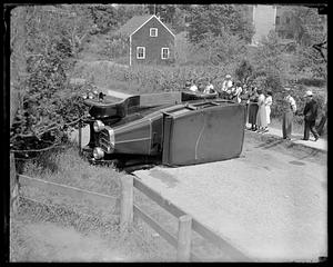 People looking at a car on its side