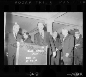Speaker David Bartley, center, with unidentified men and sign announcing House Democratic Caucus meeting