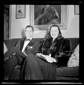 Woman in furs and man in tuxedo posing on couch