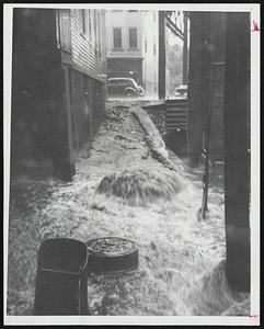 Old Faithful, Roxbury Branch-Newsboy David Morris, 15, made this shot of a drain turned geyser in an alley between Washington and Rochdale streets, Roxbury.