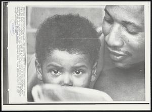 Pass Christian, Miss. -- The Sorrowful Eyes Of A Hurricane Survivor -- A small Negro boy looks sorrowfully over a chair in a refugee center at Pass Christian, Miss. Wednesday as he is comforted by his father. The family lost their home and belongings Sunday night when Hurricane Camille destroyed their town. Weather.