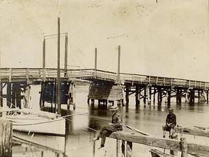 Two unidentified people sitting on bridge, probably over Bass River, South Yarmouth, Mass.