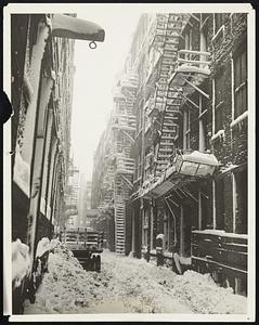 The End of the Snow which covered Chicago to a depth of nineteen inches, making a record for the month of March. Here we see an alley near the loop that was used as an emergency dumping place for the snow taken from the loop streets.
