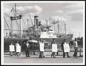 Maritime Union Pickets parade along Boston docks yesterday as 82,000 seamen and officers begin a nationwide strike. Some 7,000 members of the union live in New England but many of them are now on duty at sea.