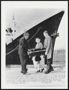 New York: Mr. and Mrs. William Angove and Rodney Angove (R) of Loveland, Colo., carry their luggage as they prepare to board the SS France at Pier 88 here 10/1. East and Gulf Coast longshoremen tied up the maritime industry in a strike which the International Longshoremen's Association called "1-00 percent effective," causing passengers to help load luggage aboard departing vessels.