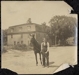 John Rodier with horse in front of mansard-roofed building