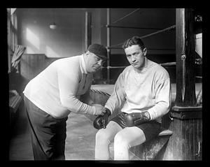 A trainer putting boxing gloves on Jim Maloney