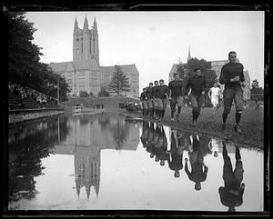 Football players running on campus, Gasson Hall in background