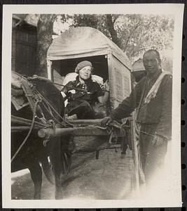Woman in cart with man standing next to her