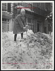 "Sounding" For Little Car - On Chestnut street, Beacon Hill, Mrs. Lyman Drake uses a broom as a probe, a trick she learned in the Alps, to find her small car buried outside her home at One Chestnut.