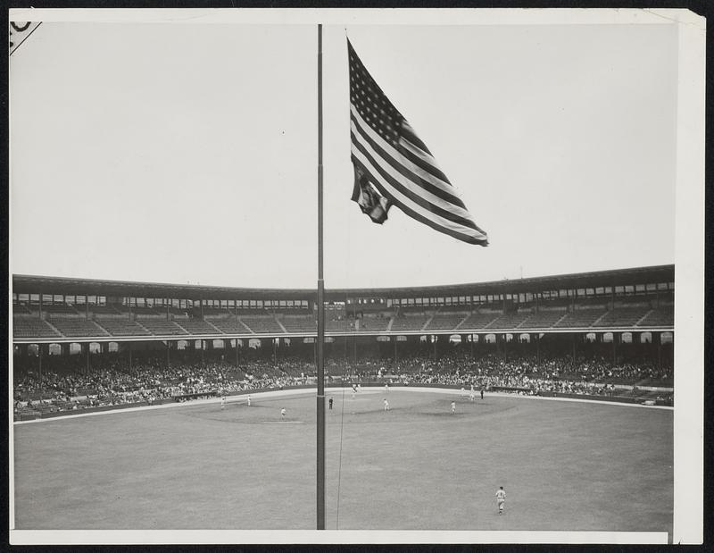 Flag at Half-Mast for Comiskey But Game Must go on. News of the death of J. Louis Comiskey, owner and president of the Chicago White Sox reached his team while they were engaged in the second game of a double-header with the Boston Red Sox and the flag in center field was immediately lowered to half staff; the game went on to completion. Mr. Comiskey, who was 54 years old, died of heart disease and pneumonia at his summer home in Eagle River, Wisc., Photo shows the center field flag at half-mast as the second game went on, at Comiskey Park.