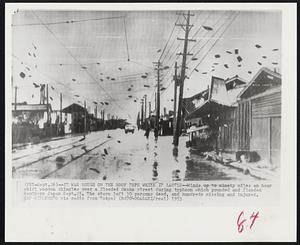 It Was Rough on the Roof Tops While it Lasted--Winds up to ninety miles an hour whirl wooden shingles over a flooded Osaka street during typhoon which pounded and flooded Southern Japan Sept. 25. The storm left 30 persons dead, and hundreds missing and injured.