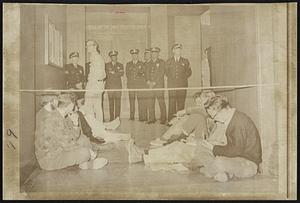 Nine demonstrators were in the second day of a sit-in today at the door leading to the offices of the Joint Chiefs of Staff in the Pentagon. The group, protesting the war in Vietnam, selected the site as "the focal point of American military policy."