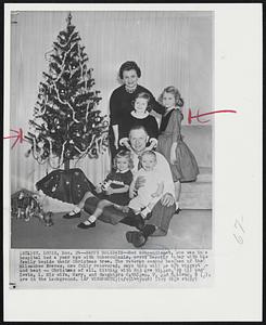 Happy Holidays -- Red Schoendienst, who was in a hospital bed a year ago with tuberculosis, poses happily today with his family beside their Christmas tree. The veteran second baseman of the Milwaukee Braves, now fully recovered, says this will be his biggest -- and best -- Christmas of all. Sitting with Red are Eileen 2 1/2 (L) and Kevin, 1. His wife, Mary, and daughters Cathleen, 7, and Colleen, 8 are in the background