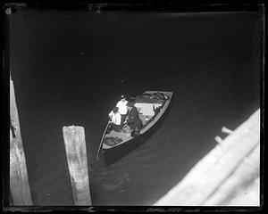 Policemen on a boat, one using a stick to explore the water