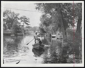 Salvaging Valuables from trailer home in the flooded West Roxbury trailer park, this couple use a boat and oarsman. What looks like a boat ride for pleasure is in reality a precaution in case the trailers have to be evacuated.