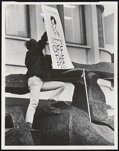 Youth hangs cartoon of Pres. Nixon on new art figure at JFK Bldg