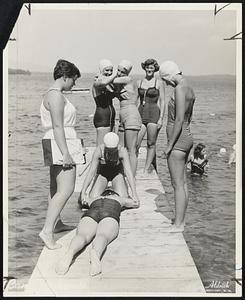 Instruction in Life Saving is given at Camp Nokomis, Lake Winnipesaukee, Gail Cullen of Winchester applies artificial respiration to Cathie Town of Winchester under the eye of Constance Putnam of Holyoke (left), waterfront instructor. Others standing (left to right) are Margie Finn, Nancy Switzer, Louise Kugler, instructor, of Winchester, and Donna Curtin of Arlington.
