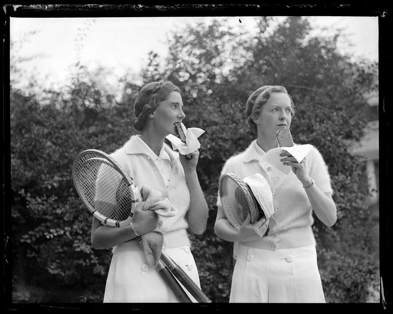 Two tennis players eating ice cream sandwiches