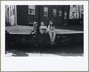 Children seated on stone wall waiting for bus on Broadway