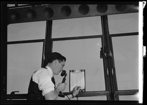 American Airlines traffic control tower. Man speaking into microphone and writing on clipboard