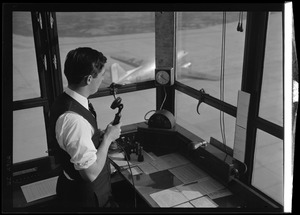 American Airlines traffic control tower. Man on microphone, airplane visible through window