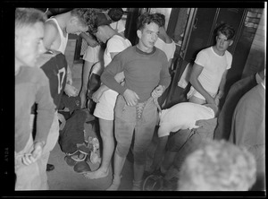 Boston English football. Player laces up football pants in crowded locker room
