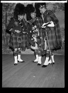 Musicians from the Scottish Highlanders Pipe Band inspect their pipes