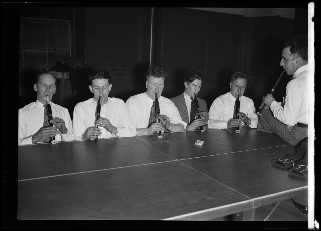 Musicians from the Scottish Highlanders Pipe Band play pipes around a table