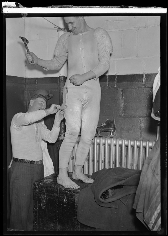 Red Casey sews a hip pad on Boston Bruins Charlie Sands