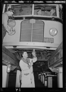 Three men perform maintenance on a bus