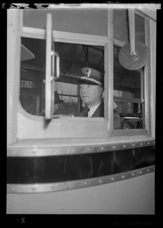 A bus driver behind the wheel of a bus, view from outside the bus