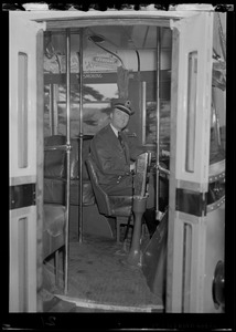 A bus driver behind the wheel of a bus, view from outside the bus