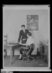 Do/More Chairs advertisement, woman seated in chair with a man leaning on the desk