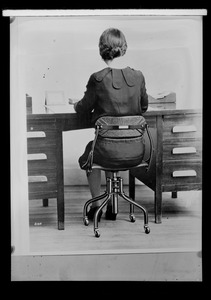 Do/More Chairs advertisement, woman seated at a desk, from behind
