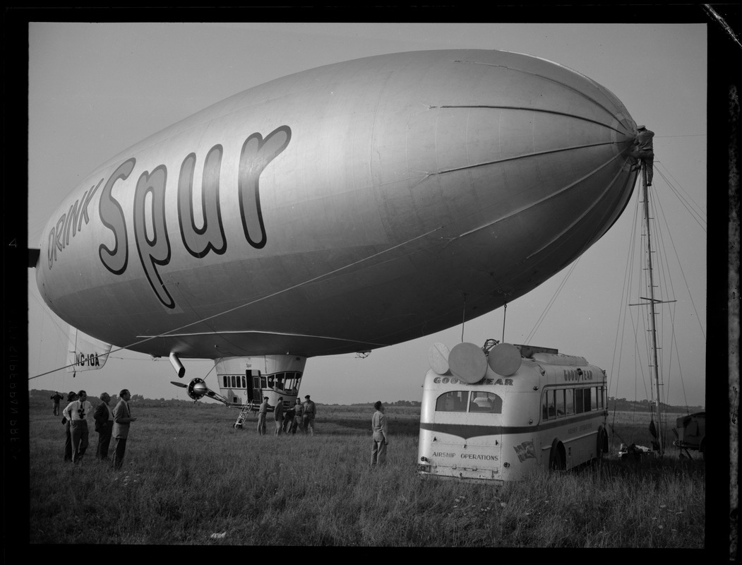 Man on tower ties down blimp branded "Drink Spur"