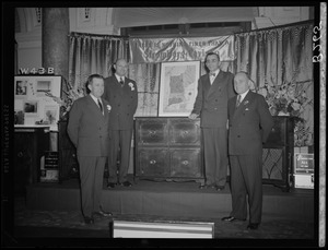 Four men in front of Stromberg Carlson presentation