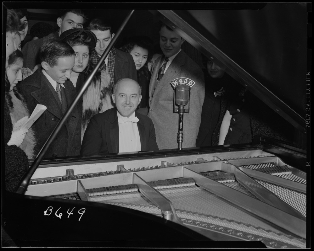 Man plays the piano surrounded by people at the Essex Hotel FM Show