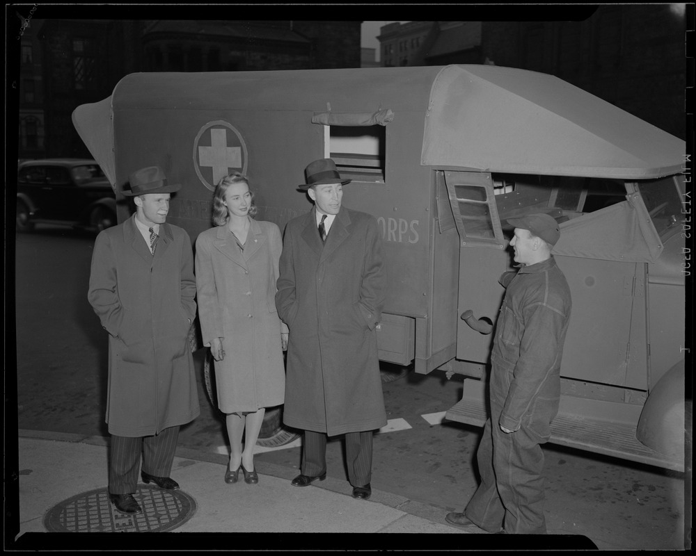 Clapper, Crowley, and model talking to a man in front of ambulance